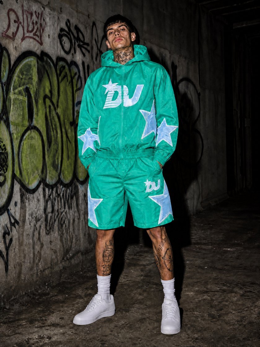 Model wearing custom green nylon hooded jacket and shorts set with star applique by DUOCAIYEARS